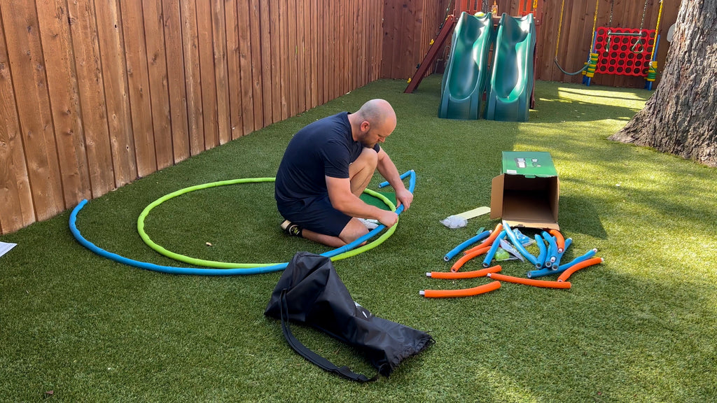Man crouched in backyard assembling foam rings from The Backyard Golf Game.