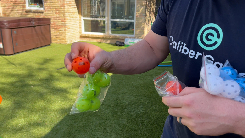 Man holding bags of plastic golf balls in backyard.