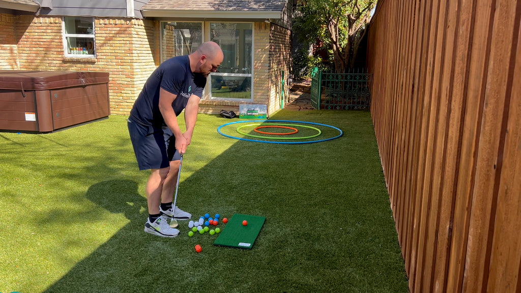 Man stands in backyard putting golf balls.