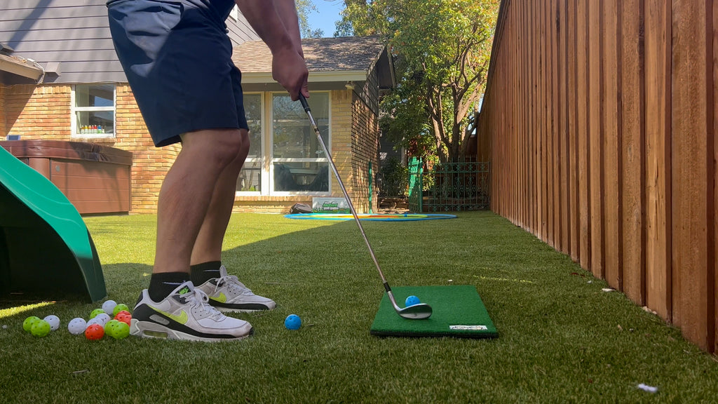 Man stands in backyard with The Backyard Golf Game putting golf balls.