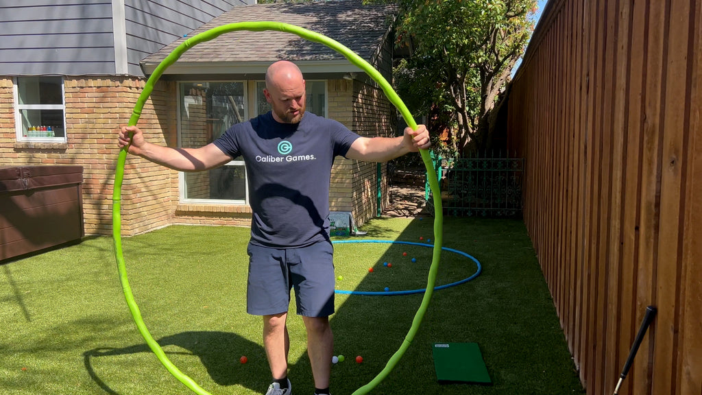 Man standing in backyard holding large green foam ring.