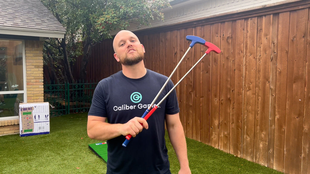 Man stands in backyard holding two Putterball golf clubs.