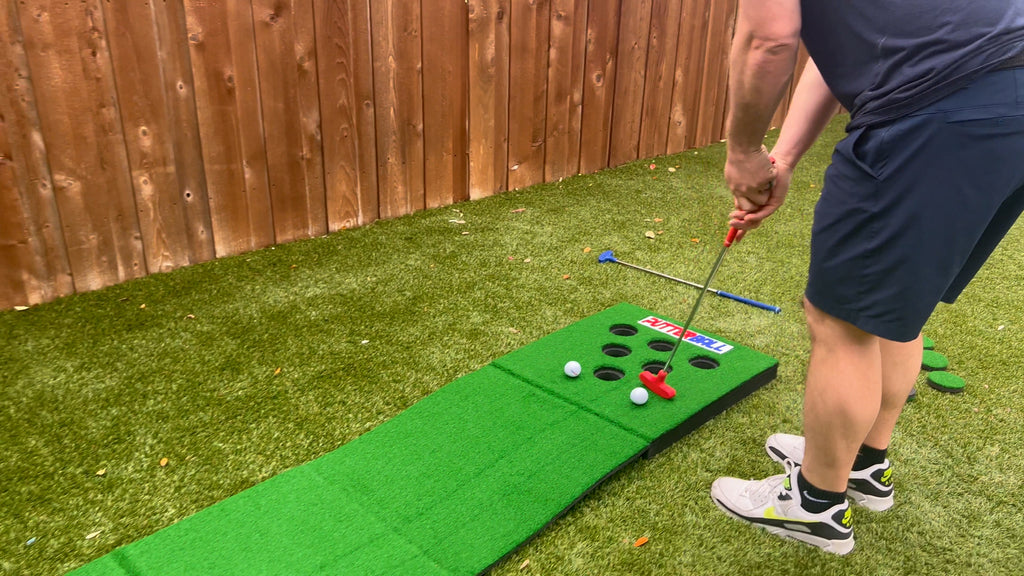 Man stands in backyard putting golf balls on Putterball green.