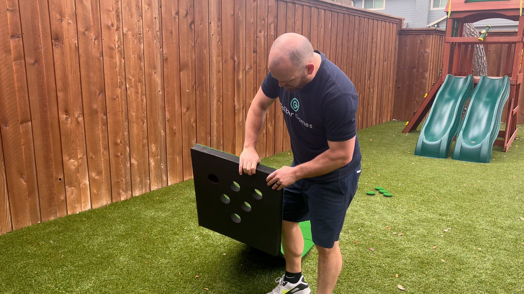 Man stands in backyard assembling Putterball green.