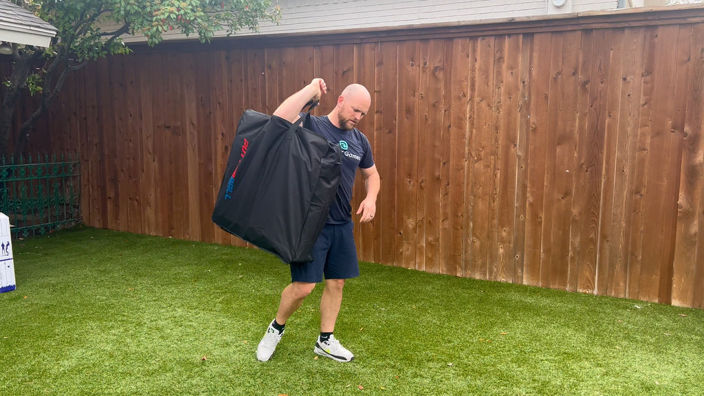 Man stands in backyard picking up Putterball nylon carry case.