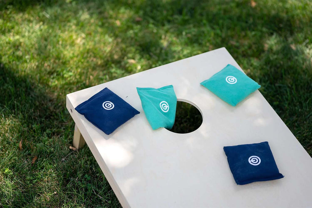 Close up of cornhole board on grass with bean bags on top