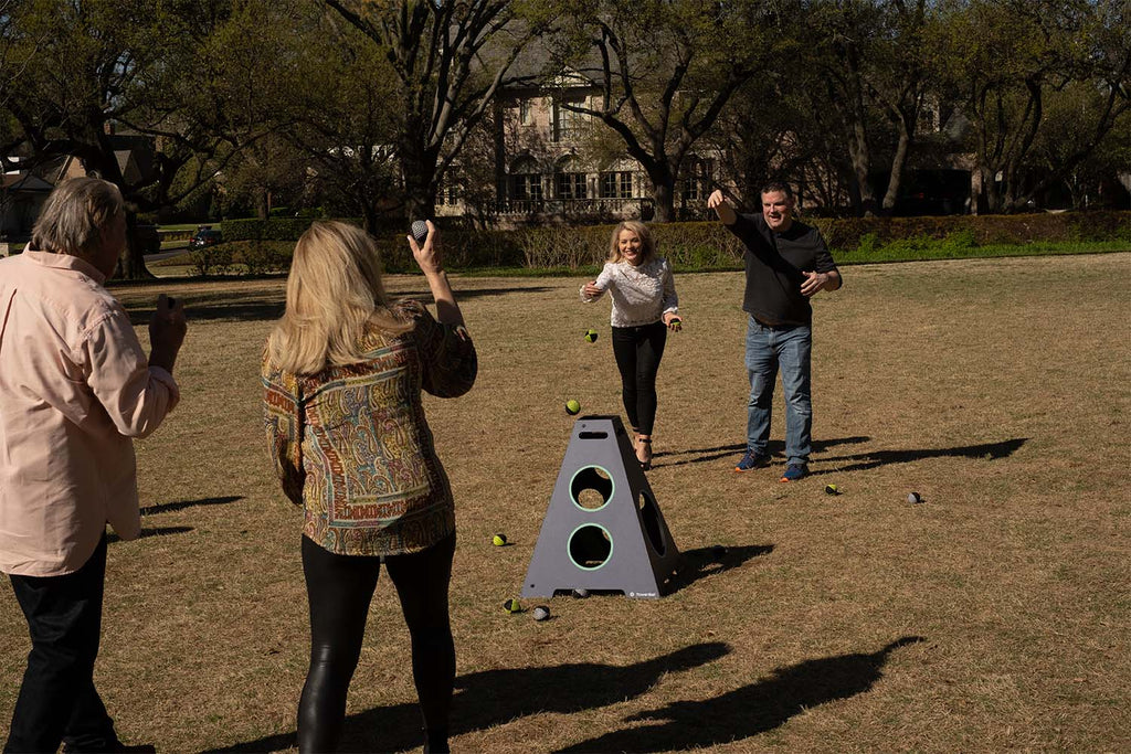 Four Friends playing Tower Toss Game In a Grassy Field