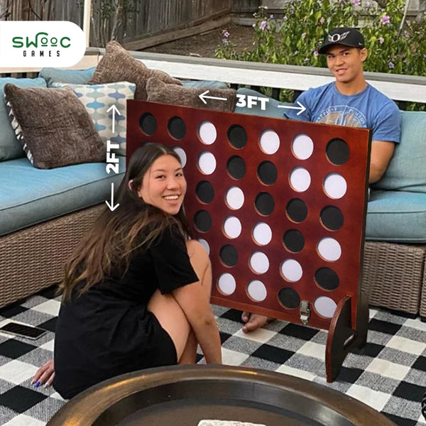 Friends sitting outside playing giant sized 4-in-a-row game