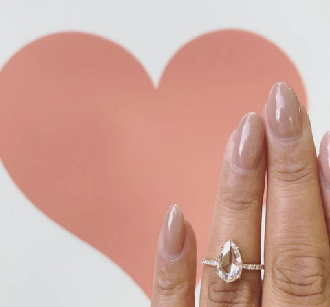 A rose cut pear shaped diamond sits on a yellow gold diamond band