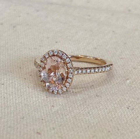 an oval cut morganite is set into a rose gold diamond halo ring setting