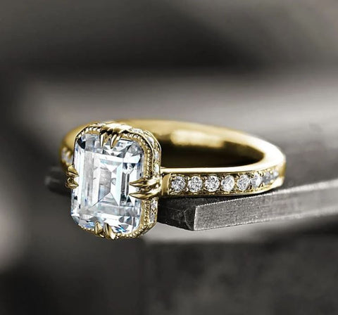 an emerald cut diamond is set into a vintage inspired ring with a hidden halo