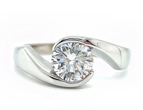 a round brilliant cut diamond is set into a white gold bypass style setting
