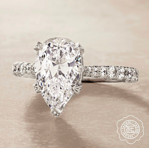 a pear cut diamond on a platinum diamond encrusted ring setting
