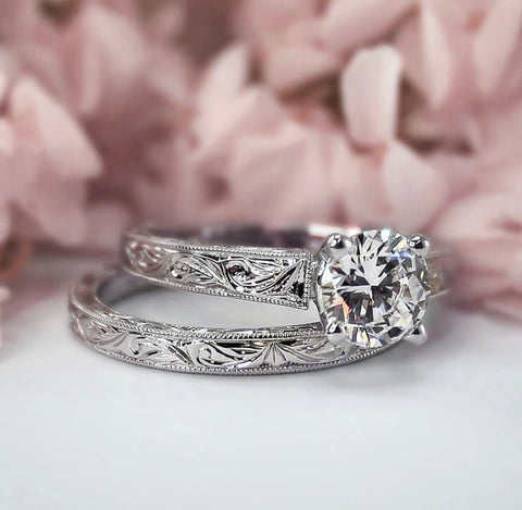 a white gold diamond solitaire engagement ring with hand carving and milgrain edges complete with matching wedding band