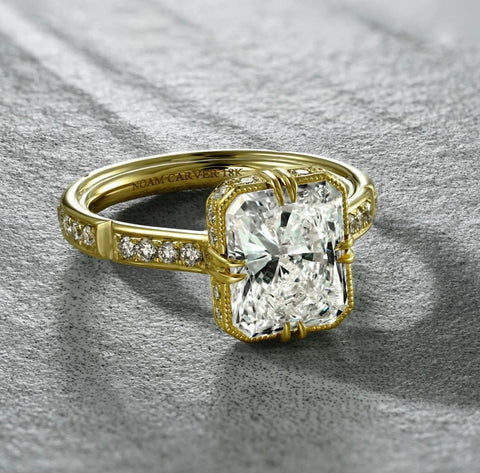 an emerald cut diamond is set into a vintage inspired yellow gold diamond band setting