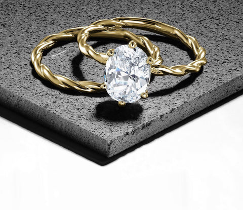 an oval cut diamond on a slim yellow gold twisty band