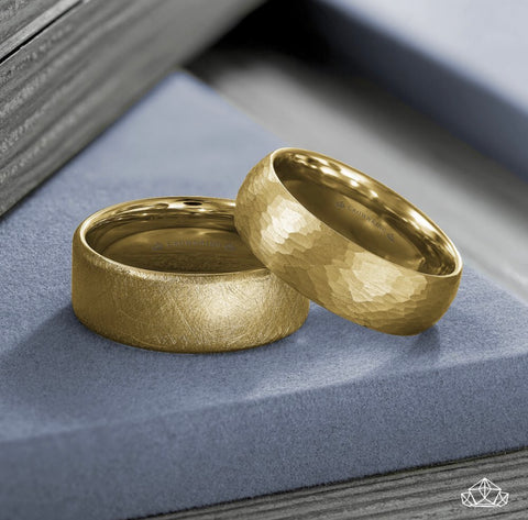 two yellow gold wedding bands, one has a hammered finish and one has a diamond wire brush finish