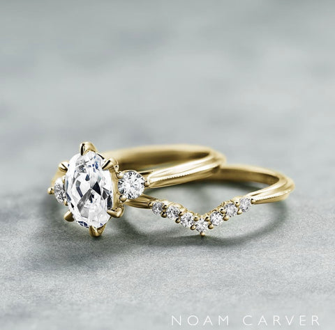 a yellow gold three stone engagement ring with a contoured diamond wedding band