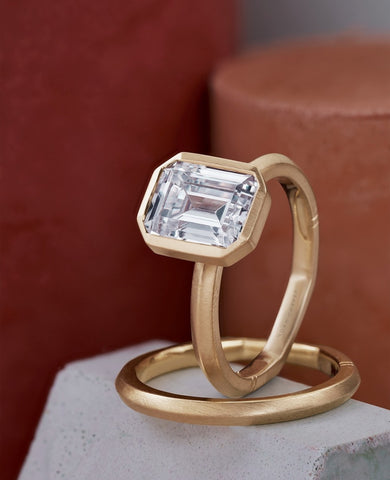 Yellow gold engagement ring bezel set with an emerald cut diamond