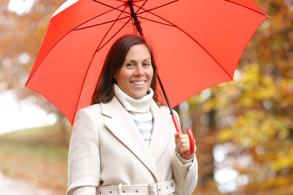 Lady wearing coat and red umbrella smile