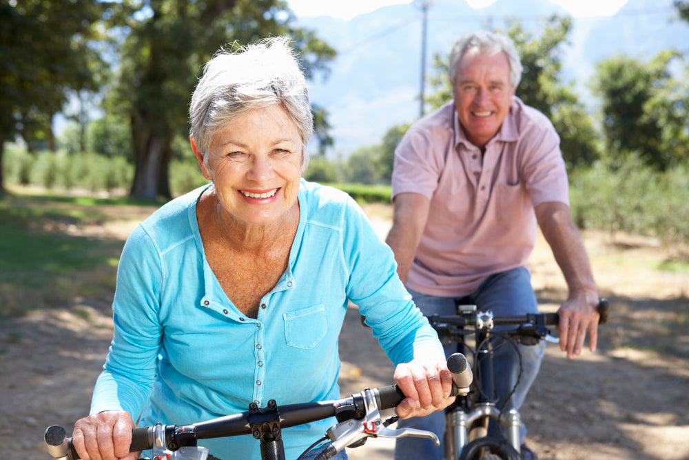 Elderly couple smiling while riding a bicycle