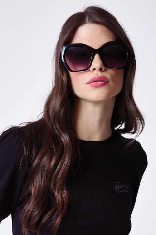 A brunette lady wearing black oversized sunglasses with gradient smoke lenses