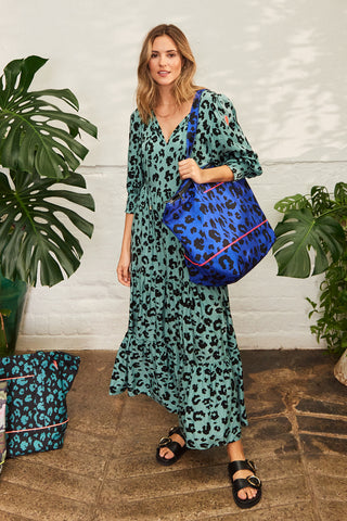 A lady wearing a Scamp & Dude dress carrying a blue with black leopard & lightning bolt print Weekender bag