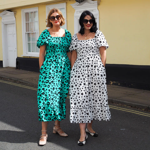 Emma Paton and Claudia Beresford with their hands in their pockets wearing Scamp & Dude Shirred Midi Dresses and sunglasses 