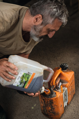 Homme qui verse une huile de synthèse dans un bidon de carburant 