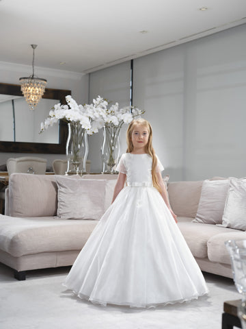 girl age 8yrs standing by sofa in a long white holy communion dress