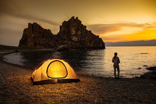 woman camp tent beach ocean sunset