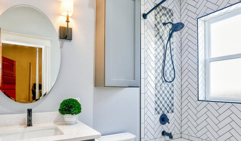 Salle de bain avec douche carrelée et miroir rond