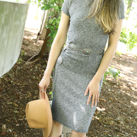 Model wearing Tooled Oval Concho Chain Belt in grey dress