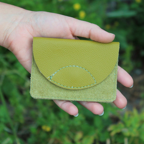 Hand with a small wallet made of green recycled leather