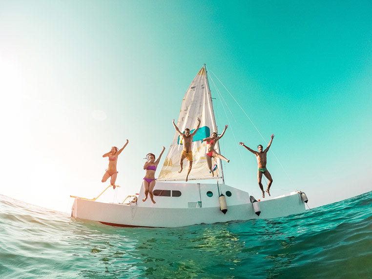 Friends diving from a sailboat