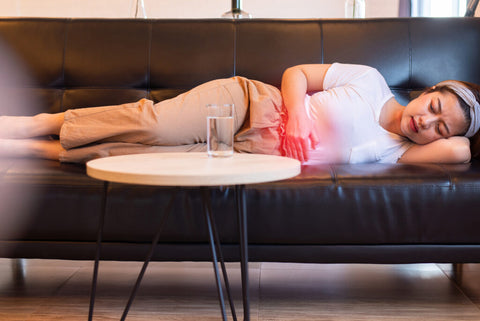 Femme allongée sur un canapé qui a des douleurs menstruelles 