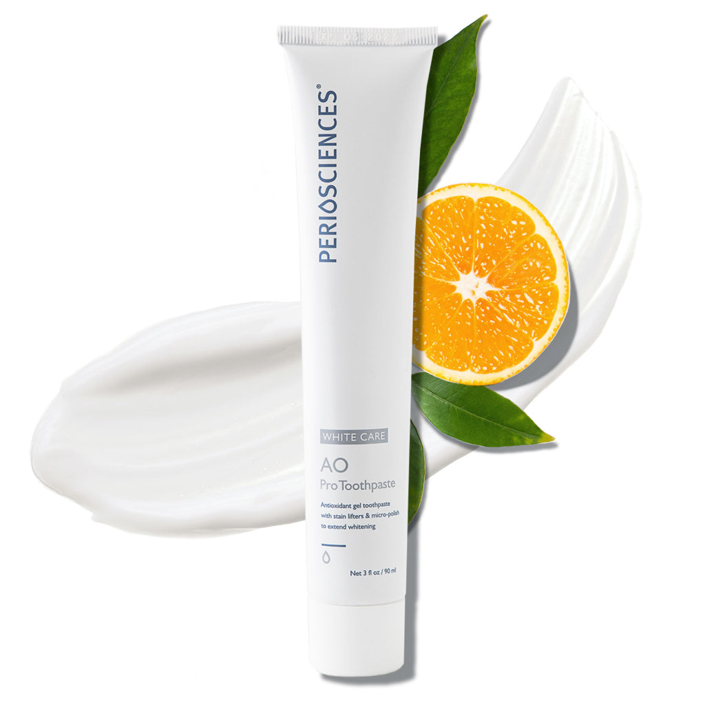 Toothpaste tube with a smear of toothpaste and a sliced orange with leaves.