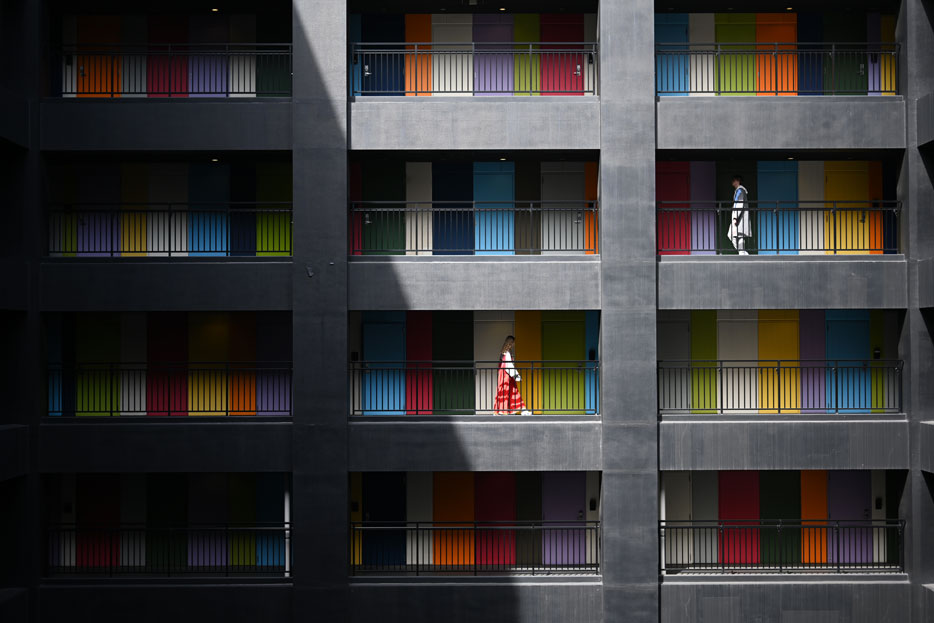 A woman wearing a red dress walking along a colorful wall of a building