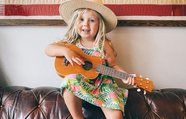 Girl learning to play the guitar like her parent