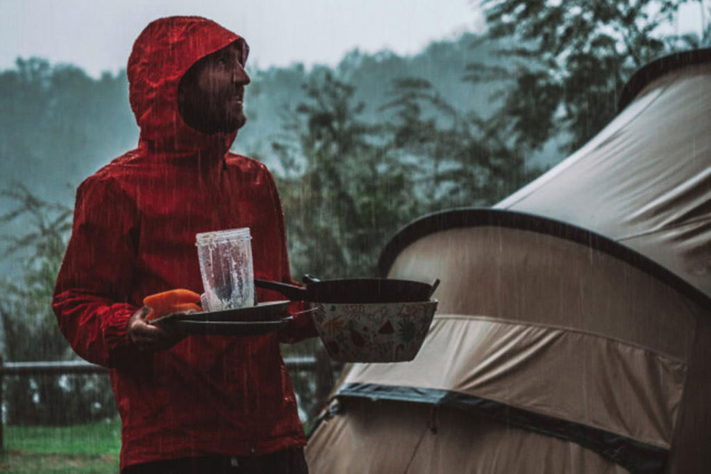 A camper carrying dirty dishes under the rain