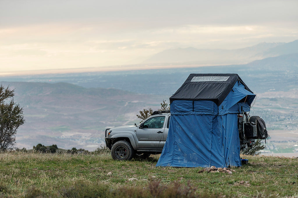 A car with a blue rooftop tent in a mountainous area