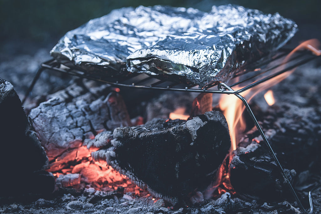 Foil packets cooking above a campfire