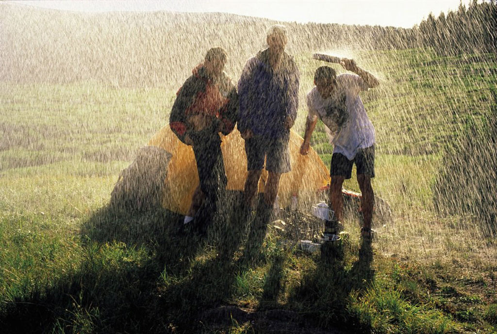 People standing at a campsite under heavy rain