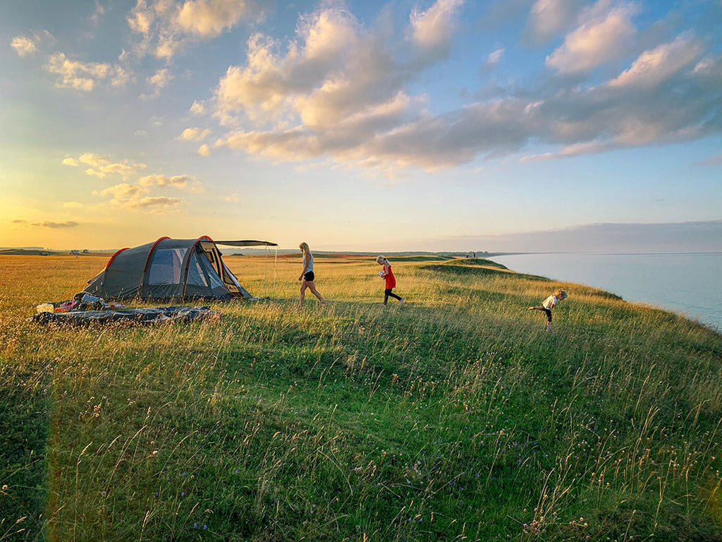 A woman with two kids camping at a lakefront