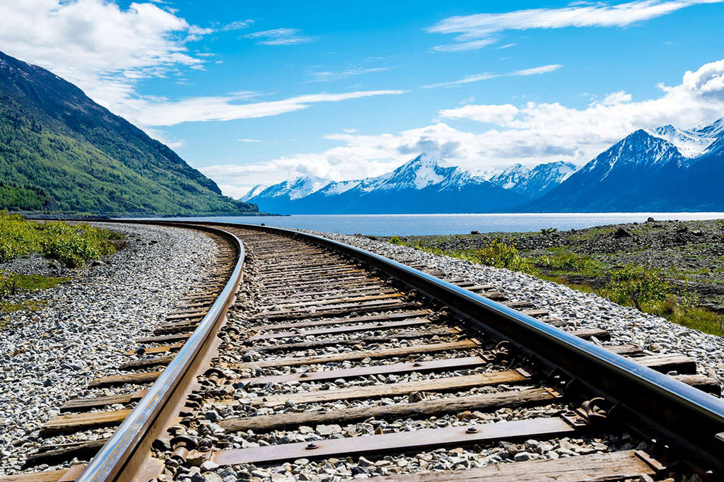 A railroad track with a view of the mountains and a lake