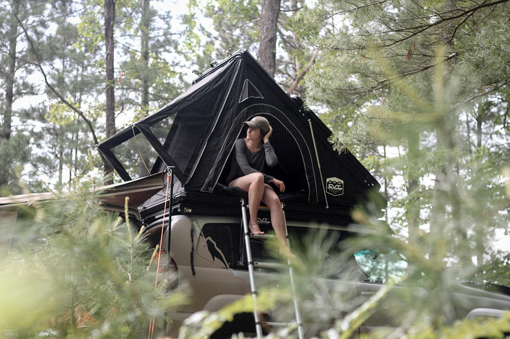 A woman sitting in a vehicle rooftop tent