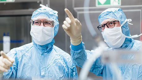 2 doctors in cleanroom attire work together