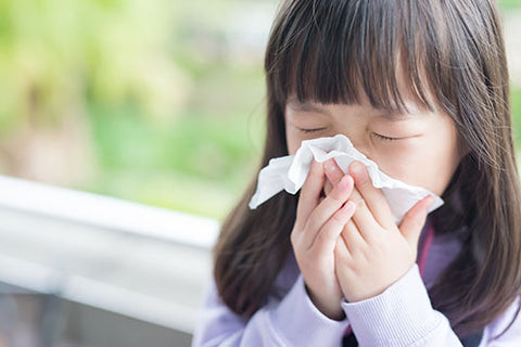 Child sneezing into a tissue.