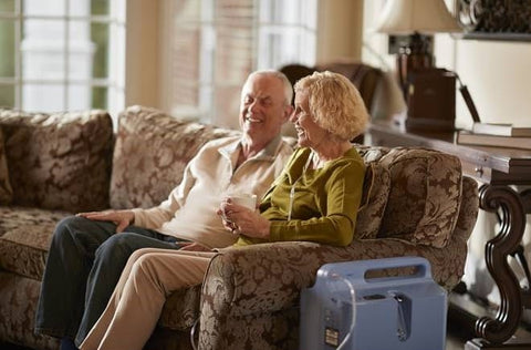 Elderly couple talking next to an oxygen concentrator