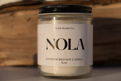 NOLA candle by Parish Scents in a glass jar candle vessel with a white label and black text